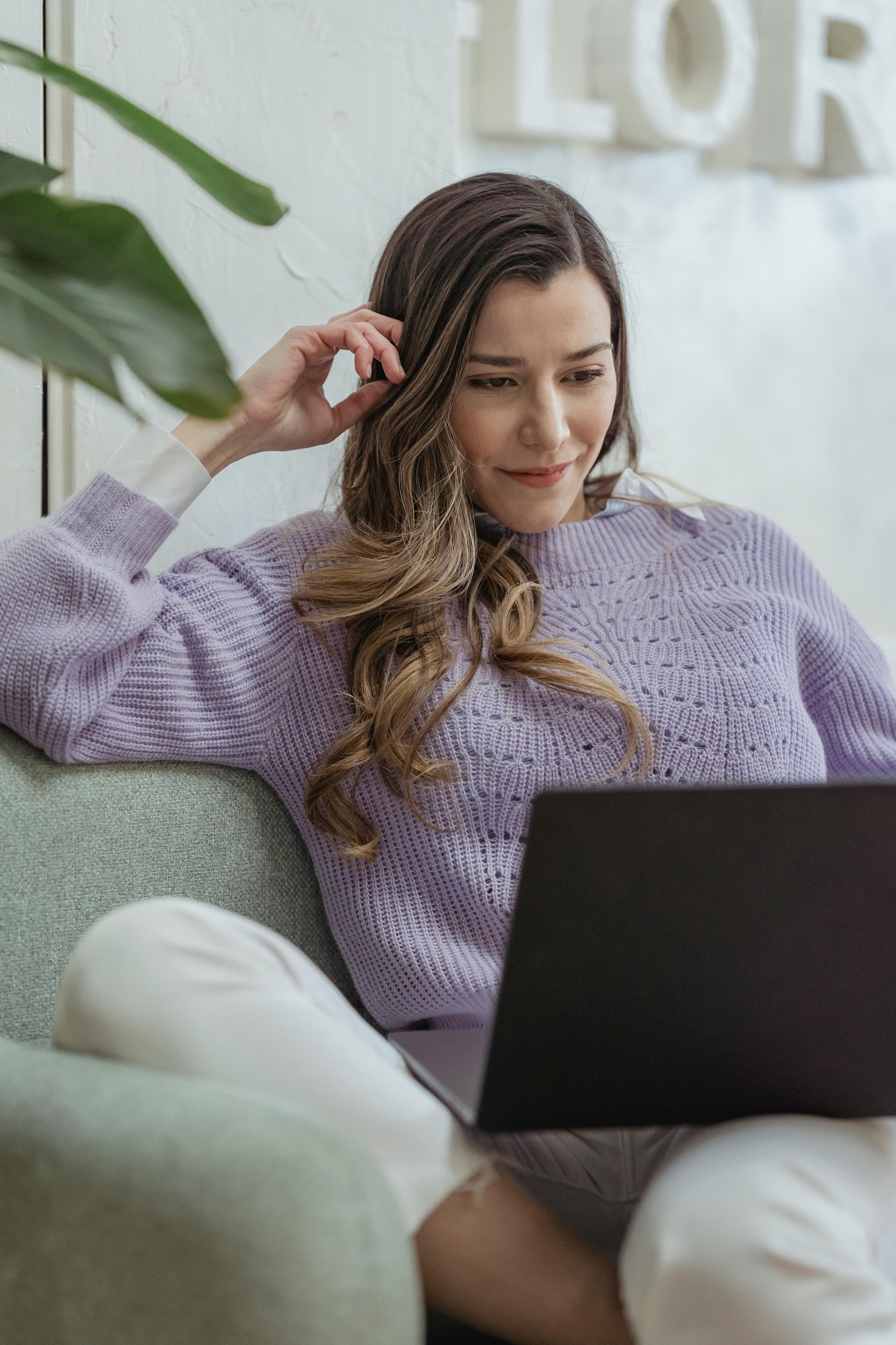 A woman sitting comfortably on a couch, focused on her laptop, exuding productivity and ease—a representation of exploring the best keyword research tools online.