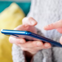 A woman holds a smartphone in her hands.