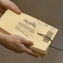 A poll worker holds a stack of ballot envelopes.