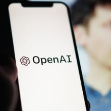 openai logo on a smartphone in front of an image of ceo sam altman