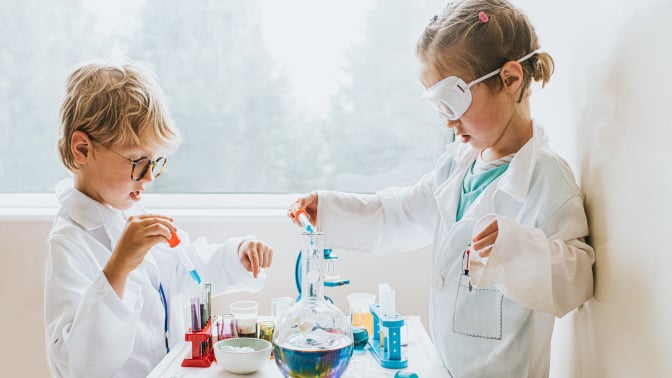 A girl and boy play with a lab science kit.