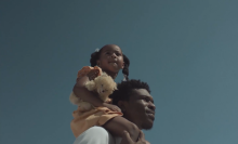 A father carries his daughter on his shoulders.