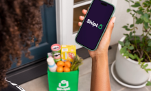 Person holding a smartphone with the Shipt logo