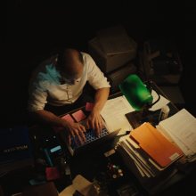 A man looks over a stack of papers in a dimly-lit attorney's office.