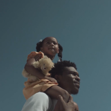 A father carries his daughter on his shoulders.