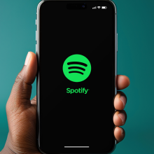 Person holding a smart phone with the spotify logo on it