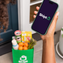Person holding a smartphone with the Shipt logo